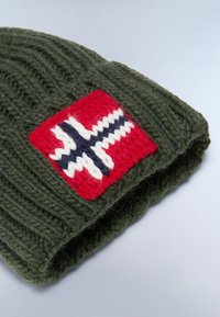 Vihreä neulottu pipo, jossa on käännetty reuna, ja joka sisältää erottuvan suorakulmaisen tarran punaisella, valkoisella ja sinisellä ristikuviolla.