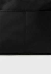 Borsa a tela nera con texture liscia, caratterizzata da una cucitura prominente e senza accessori o dettagli visibili. Design rettangolare semplice.