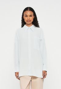 Helles blaues Langarmhemd mit Kragen, Knopfleiste und Brusttasche. Es zeichnet sich durch einen strukturierten Stoff und eine lockere, entspannte Passform aus.