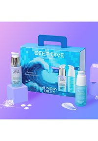 Deep Dive Hydration Set i en blå pixelmasketæske. Indeholder to flasker: Good Genes (sølv og blå) og Tidal (lyseblå).