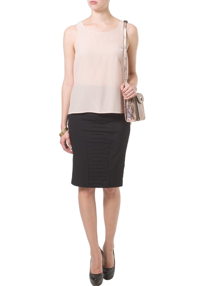 Ljusrosa ärmlös topp med en mjuk yta, kombinerad med en figurnära svart kjol med vertikala veck, kompletterad med en metallisk handväska.