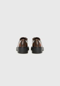 Chaussures en cuir marron avec une finition lisse, de forme arrondie et des semelles en caoutchouc noires. Présente un talon bas et un design décontracté. Vue arrière montrée.