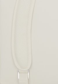 Krém színű párnázott szövetpánt, amely hálós textúrával függőlegesen fut egy sima szövet háttérrel szemben.