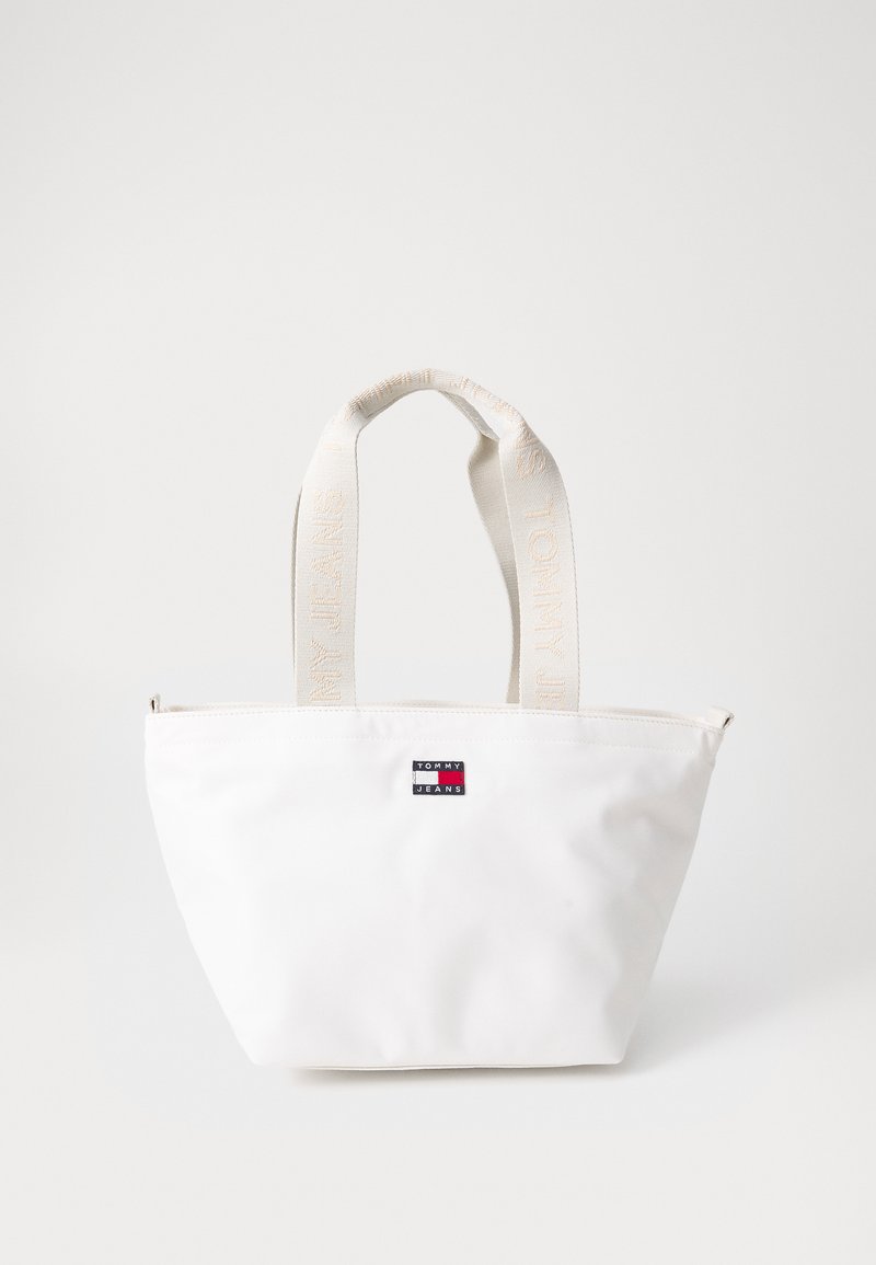 Balta rankinė pagaminta iš lygios medžiagos, su užtrauktuku, plokščiu dugnu ir logotipo užkliju, su kreminės spalvos rankenomis, pažymėtoms "TOMMY JEANS."