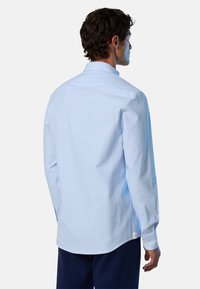 Camisa de dress de rayas azul claro con mangas largas, puños de botón y un cuello estándar. Tela suave con una textura sutil, dobladillo ligeramente curvado.