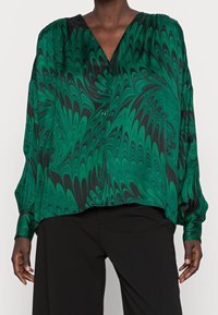 Grön- och svartmarmorerad blus med V-ringning, långa ärmar, knappdetaljer och en lös passform, tillverkad av ett mjukt, lätt tyg.