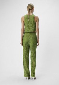 Top corto de encaje verde y pantalones de pierna ancha a juego, con intrincados patrones florales y un acabado texturizado. Silueta elegante y ajustada.
