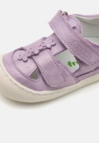 Lila lädersandal med utskärningsdesign, blommiga detaljer och kardborreband. Har en strukturerad yta och gummisula.