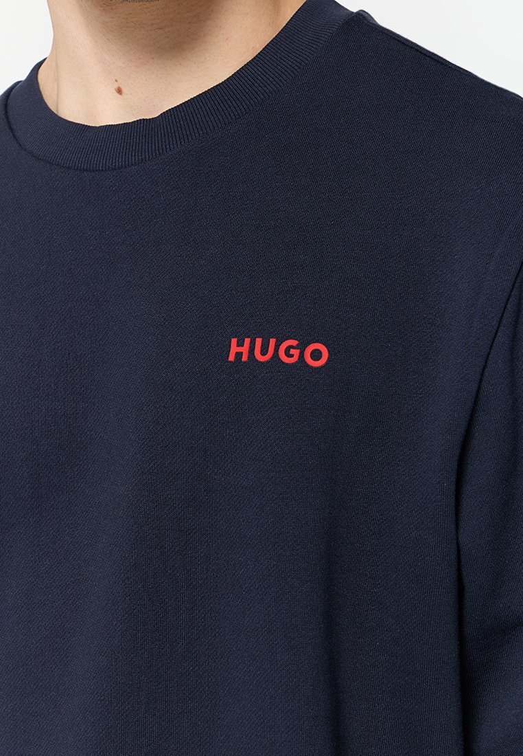 Dunkelblaue Sweatshirt aus glattem Stoff mit rotem "HUGO"-Logo auf der Brust. Rundhalsausschnitt und gerippte Manschetten.