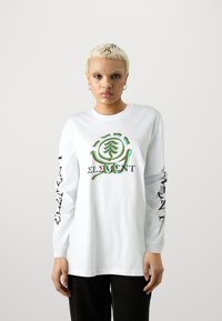T-shirt bianco a maniche lunghe con un logo grafico colorato sul davanti e un design in testo nero sulle maniche. Tessuto di cotone morbido con una vestibilità rilassata.