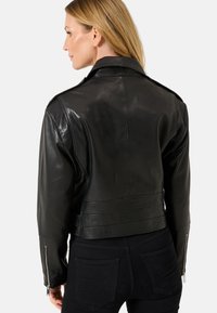 Zwarte leren cropped jas met een klassieke kraag, ritssluitingen op de manchetten en horizontale stikdetails op de rug. Gladde textuur.