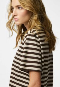 Prugasta majica kratkih rukava u bež i smeđoj pamučnoj tkanini, s okruglim izrezom. Dizajn uključuje horizontalne pruge različitih širina.