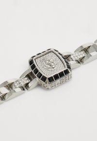 Pulsera de cadena de plata con un emblema central de león cuadrado que presenta un detallado intrincado, acentos en negro y piedras transparentes incrustadas en los eslabones.