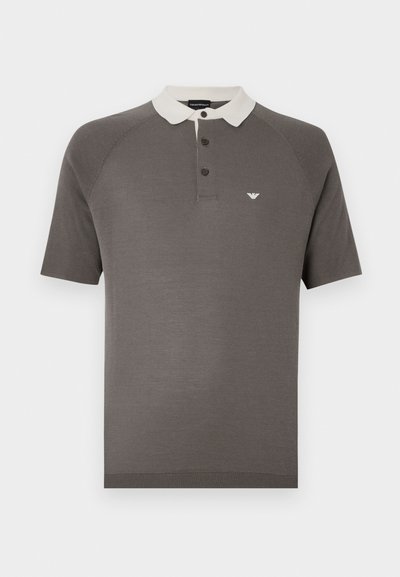 Polo gris en tissu doux avec un col blanc contrastant, une patte à trois boutons et un petit logo sur la poitrine.