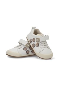 Zapatitos blancos para toddlers con suelas beige, parches de brillantina en forma de corazón y correas de Velcro sobre los cordones, exhibidos sobre un fondo blanco.