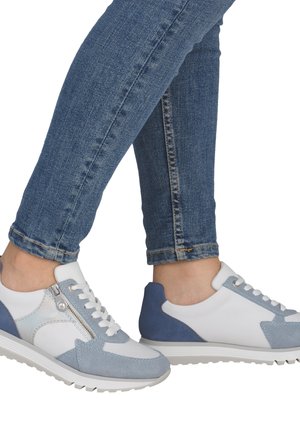 Baskets bleu clair et blanc en mélange de matériaux lisses et en daim. Dotées d'une fermeture éclair latérale, de lacets et d'une semelle texturée. Les jeans sont moulants.