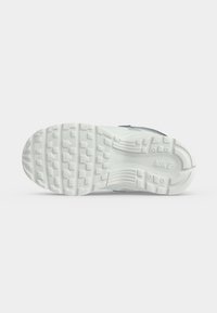 Σόλα ενός λευκού αθλητικού παπουτσιού Nike με υφασμένο σχέδιο πέλματος και ορατό λογότυπο Nike στην περιοχή της φτέρνας.