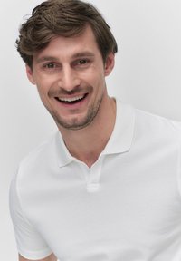 Vit polo-shirt med krage, korta ärmar och strukturerad tyg. Skjortan har en rak passform och minimal detaljering.