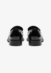 Black patent leather shoes with a smooth finish, rounded toe, and a low heel. Features a slip-on design and minimal stitching detail.