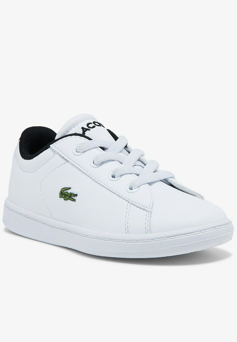 White low-top sneaker with white laces, black inner lining, and green crocodile logo on the side.
