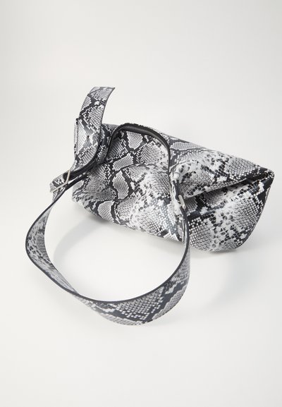 Sac à main imprimé serpent avec un design plié, en noir et blanc, présentant une texture lisse et une large bandoulière pour le transport.