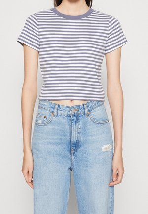 Female wearing a cropped, short-sleeve, grey and white horizontal striped shirt paired with high-waisted light blue distressed jeans.