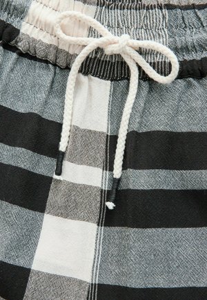 Schwarz-weiße Karoshorts mit einem elastischen Bund und einer weißen Kordel. Der Stoff hat eine strukturierte Oberfläche mit kontrastierenden Streifen.