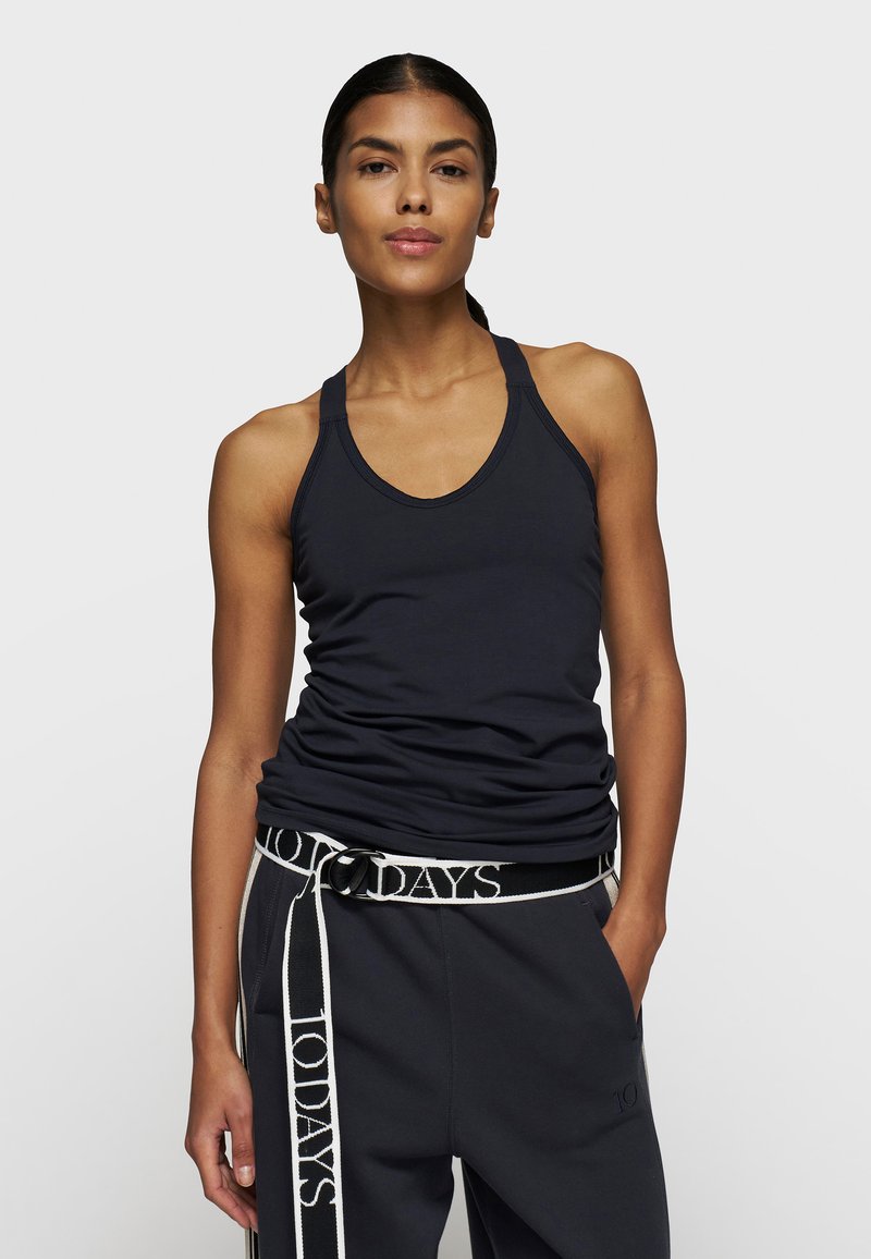 Schwarzes ärmelloses Tanktop mit rundem Ausschnitt und tailliertem Schnitt, kombiniert mit dunklen Sweatpants mit Logo-Bund und seitlichen Akzenten.