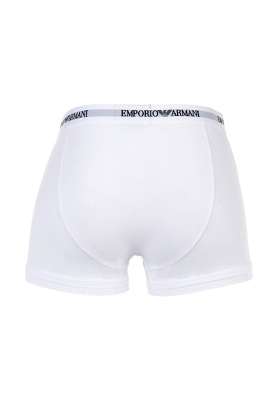 Λευκά ανδρικά μπόξερ με πλατιά λευκή ζώνη μέσης που φέρει το μαύρο λογότυπο Emporio Armani και το έμβλημα αετού, εμφανιζόμενα από πίσω.