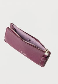 Torebka na zamek z teksturowanej fioletowej skóry z srebrnym zamkiem. Wnętrze wyściełane jasnofioletową podszewką i wyposażone w małą metalową pętlę do zawieszenia.