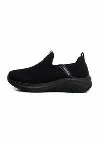 Zapatos negros sin cordones con parte superior de malla, diseño texturizado y suela de goma gruesa con un patrón estriado para mayor agarre y flexibilidad.