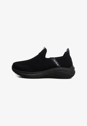 Zapatos negros sin cordones con parte superior de malla, diseño texturizado y suela de goma gruesa con un patrón estriado para mayor agarre y flexibilidad.