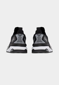 Ζευγάρι μαύρα και γκρίζα sneakers EA7, εμφανιζόμενα από πίσω, με λευκές μεσαίες σόλες και λογότυπα της μάρκας στα τακούνια και στις πλευρές.