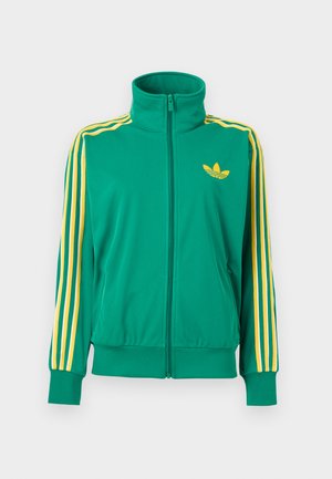 Grüne Trainingsjacke mit durchgehendem Reißverschluss, gelben Streifen an den Ärmeln und einem gelben Adidas-Trefoil-Logo auf der Brust, dargestellt auf weißem Hintergrund.