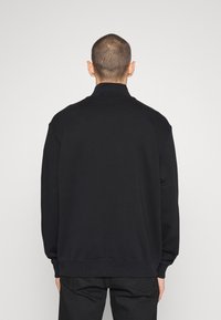 Sort, langærmet sweatshirt med høj krave, ribbet manchetter og kant, lavet af blødt materiale med en glat tekstur.