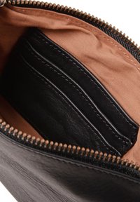 Black leather wallet interior with a zip closure, features a textured surface and brown fabric lining, includes card slots and stitching details.