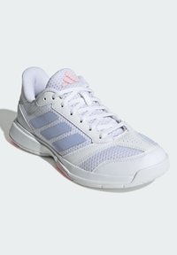 Zapatilla deportiva blanca con acentos en rosa y gris, que presenta paneles de malla, diseño con cordones y una suela texturizada para mayor tracción.