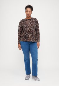 Top s leopardím vzorem, dlouhý rukáv, hnědé a černé barvy, zkombinovaný s modrými džíny rovného střihu a šedými teniskami. Hladký materiál s volným střihem.