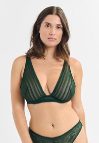 Grüner Spitzen-Bralette mit tiefem V-Ausschnitt, vertikalen Streifen und gewellten Kanten. Leichte, durchsichtige Textur und verstellbare Träger.