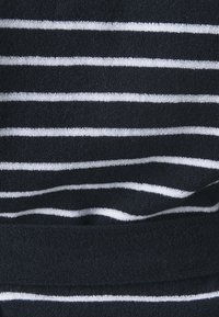 Tessuto blu navy con strisce orizzontali bianche; texture morbida con una leggera lucentezza, con strisce di larghezze variabili e un bordo ripiegato.