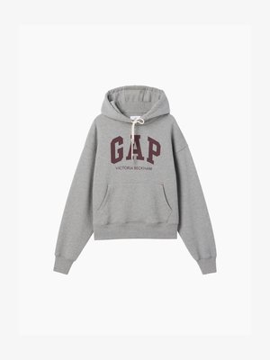 Sweat à capuche gris avec texte "GAP" bordeaux et texte plus petit "Victoria Beckham" en dessous, avec poche kangourou à l'avant et capuche avec cordon.