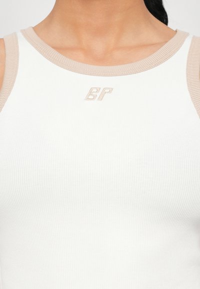 White ribbed tank top with beige ribbed trim and subtle embroidered logo in beige on the front. Slim fit, soft texture.