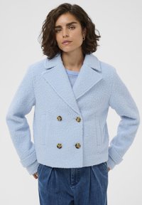 Veste bleu clair à double boutonnage en tissu texturé, présentant des boutons dorés, des revers crantés et des poches latérales.