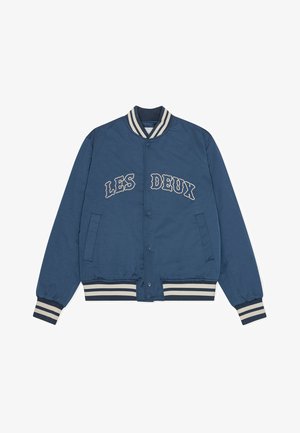 Marineblå bomberjakke med hvite striper på kragen og mansjettene. Har "LES DEUX" broderi og sidelommer. Glatt, lett stoff.