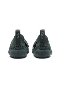 Zelene pletene cipele za nošenje bez vezica s teksturiranim gornjim dijelom, podesivim remenom i gumiranim potplatom. Imaju povlačnu traku s "Nike" brendingom.