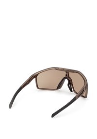 Gafas de sol ovaladas marrones con un diseño elegante y angular. Presentan lentes tintados, agarres de goma negra con textura y una montura ligera.