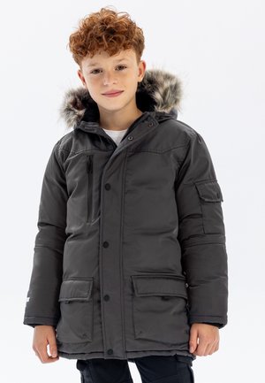 Juoda pūsta striukė su kailiniu gobtuvu, priekinėmis kišenėmis su užklotu ir užtrauktuku užsegama krūtinės kišenė. Yra mygtukų ir užtrauktuko uždarymas.