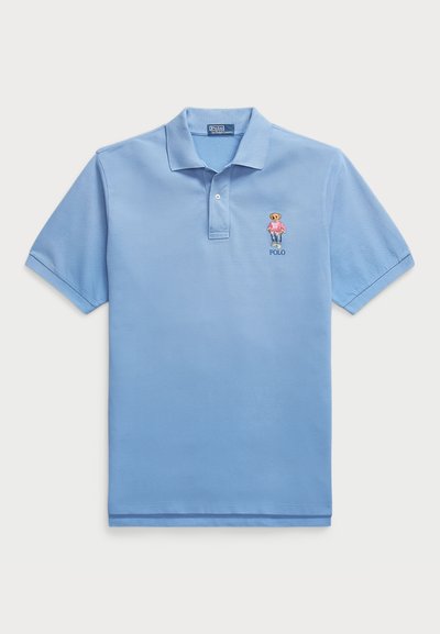 Light blue polo shirt made of cotton, featuring a three-button placket and embroidered bear logo on the left chest. Short sleeves.