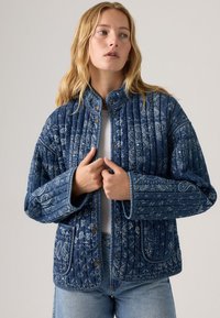 Gevoerde spijkerjack in donkerblauw met witte paisleypatronen, drukknoopsluiting, hoge kraag en brede mouwen. Voorzien van opgestikte zakken en een gestructureerde stof.