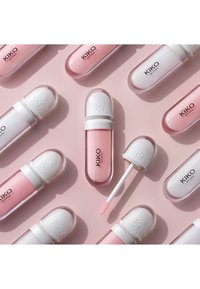 Plusieurs gloss à lèvres KIKO Milano dans des tons rose pâle sur un fond rose, une baguette de gloss retirée montrant l'embout applicateur.